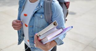 woman wearing blue denim jacket holding book